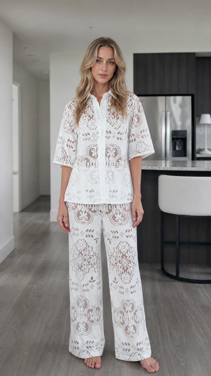 Front view of woman wearing white floral lace button-down shirt and wide-leg pants set