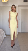Front view of yellow sleeveless midi pencil dress with front slit