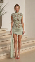 Front view of model wearing sage lace mock neck mini dress with side drape