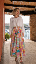 Front view of model wearing white crop top and pink multi printed maxi skirt