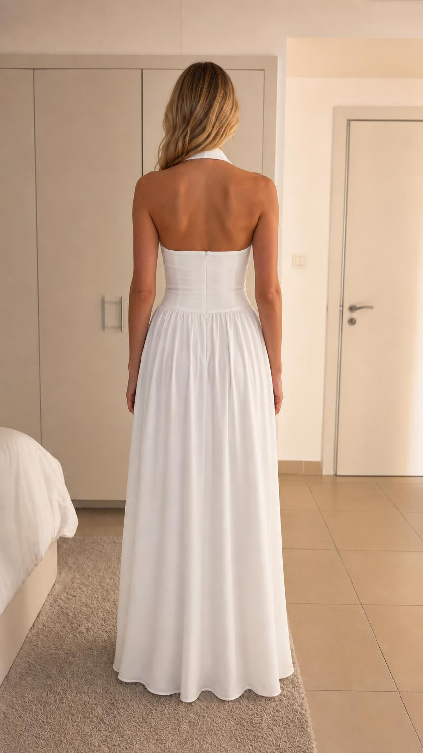 Back view of woman showing halter straps and back of white maxi dress