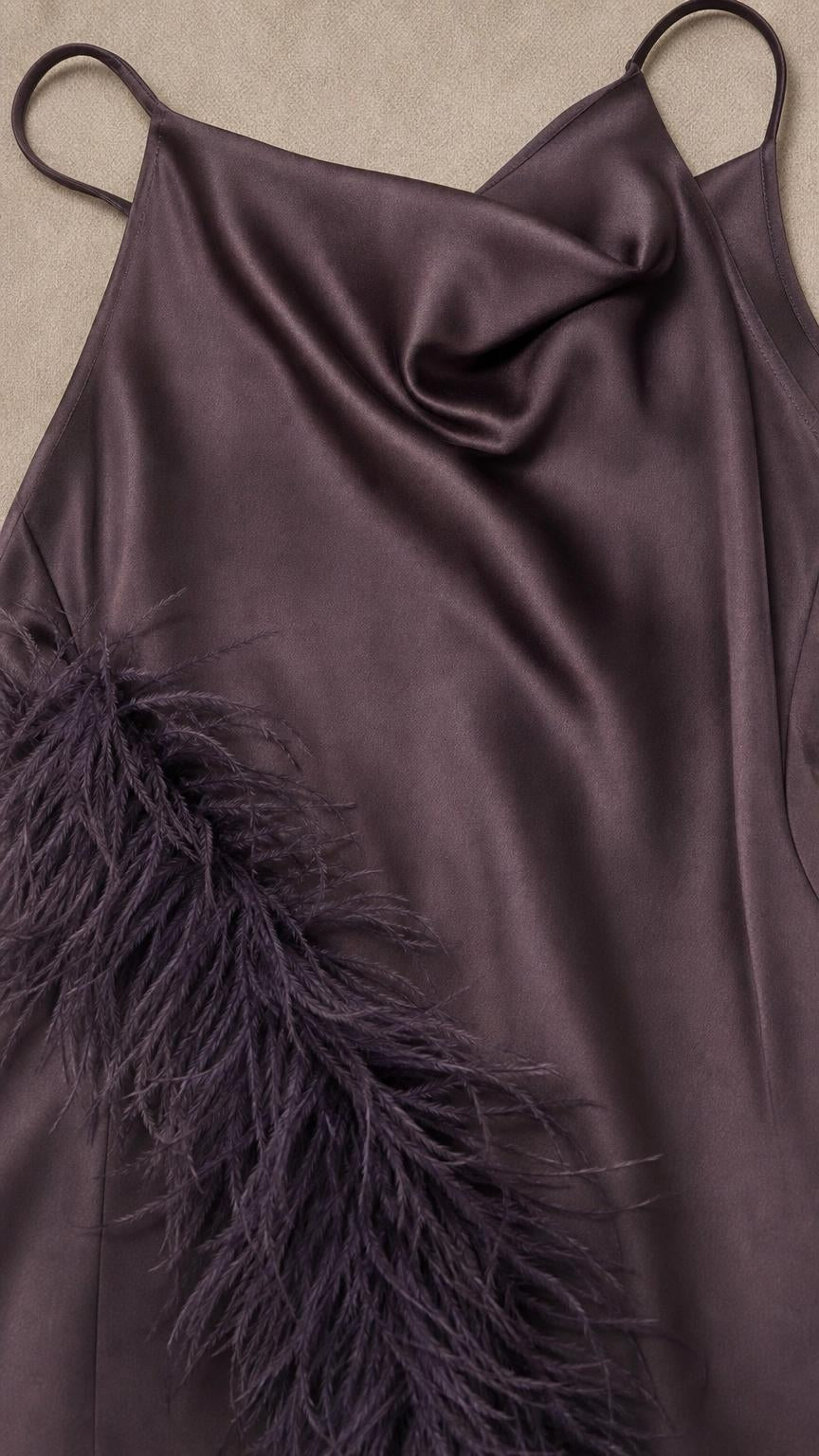 Close-up detail of dark purple satin fabric and feather trim