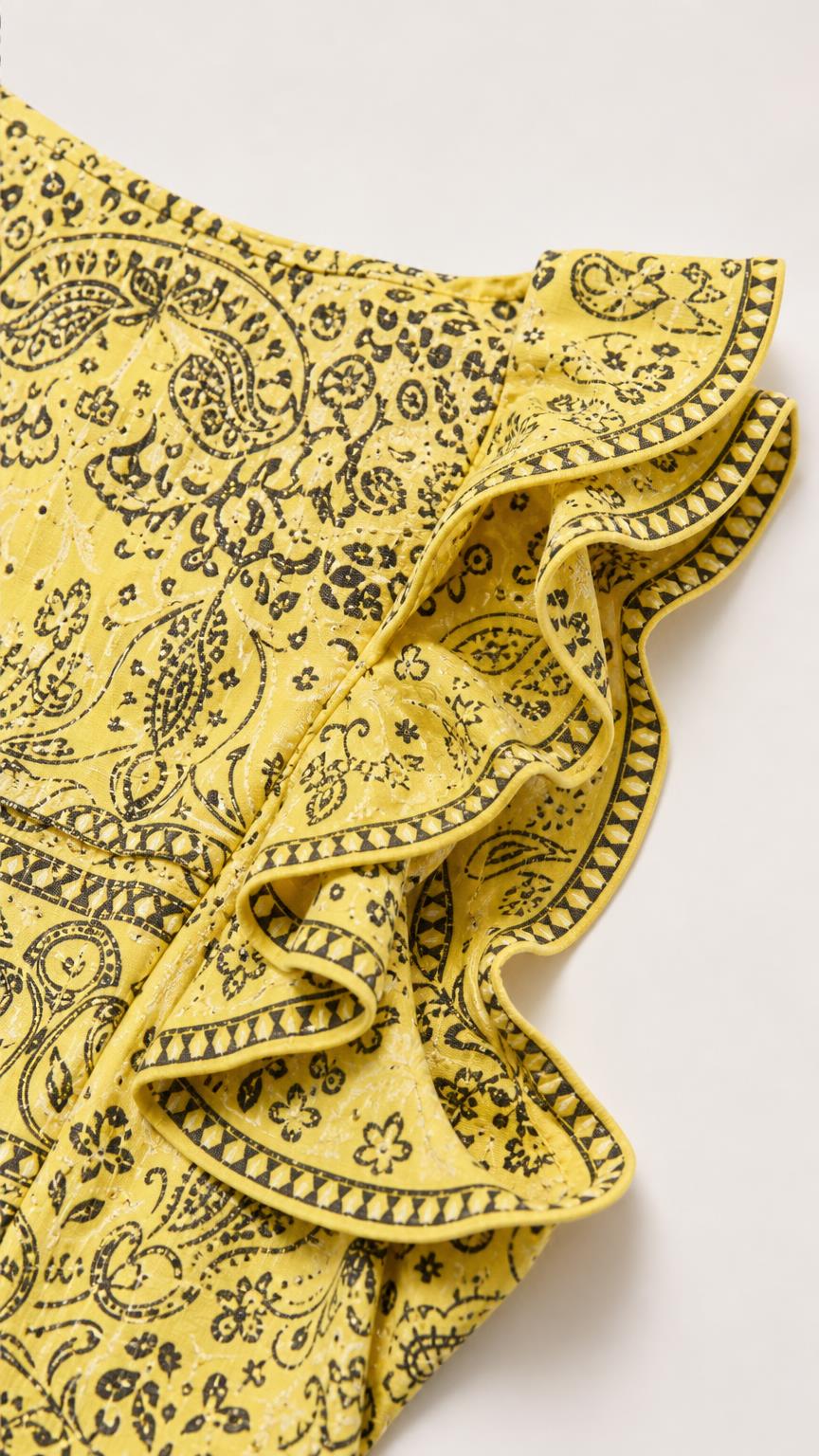 Close-up detail of yellow paisley patterned fabric and ruffle trim