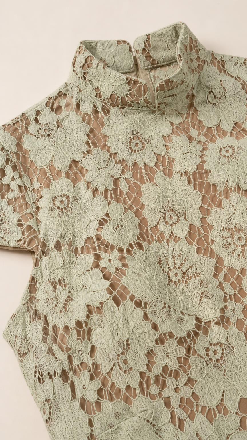 Close-up detail of sage floral lace fabric and mock collar
