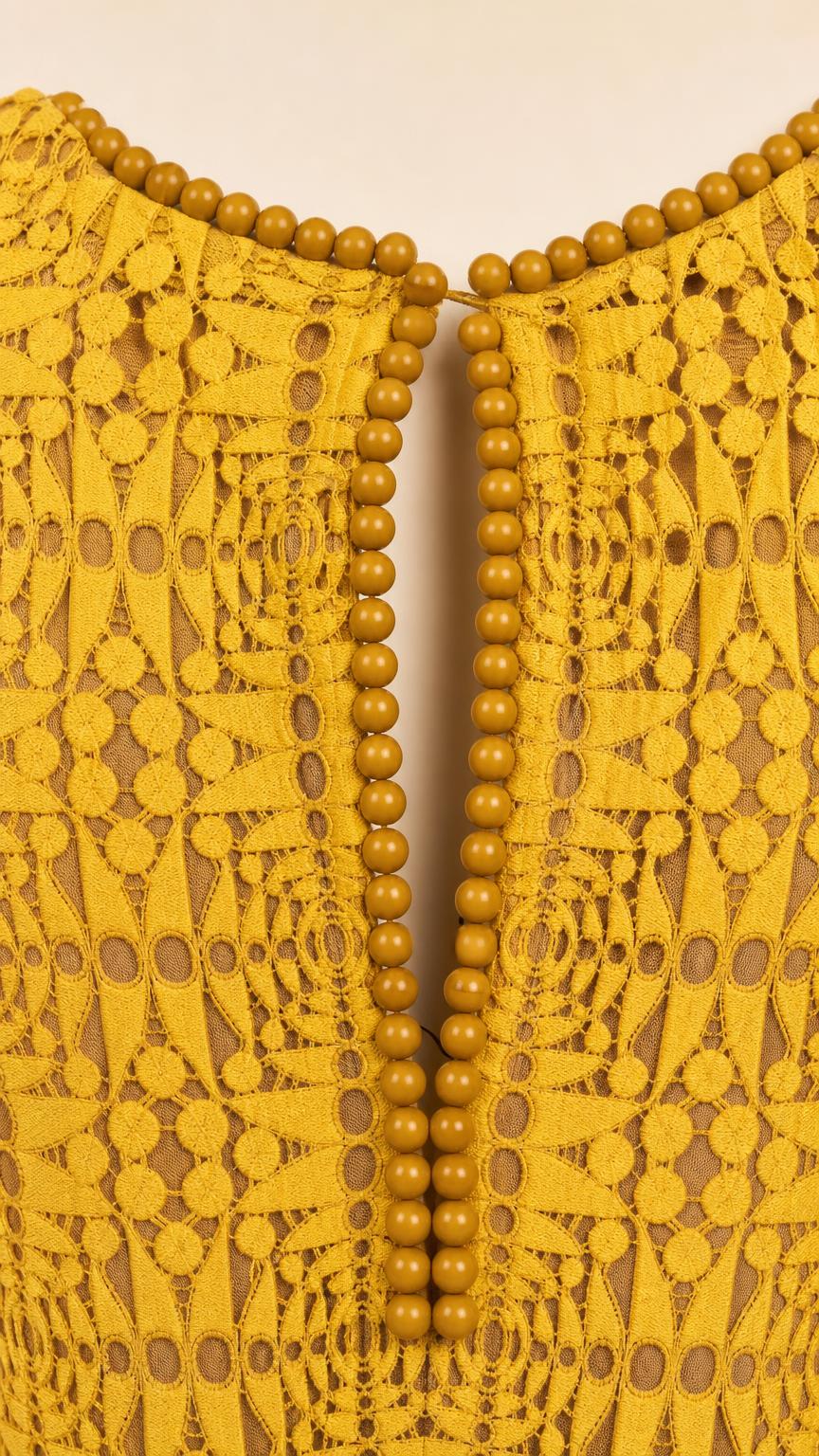 Close-up detail of beaded neckline trim on yellow lace dress