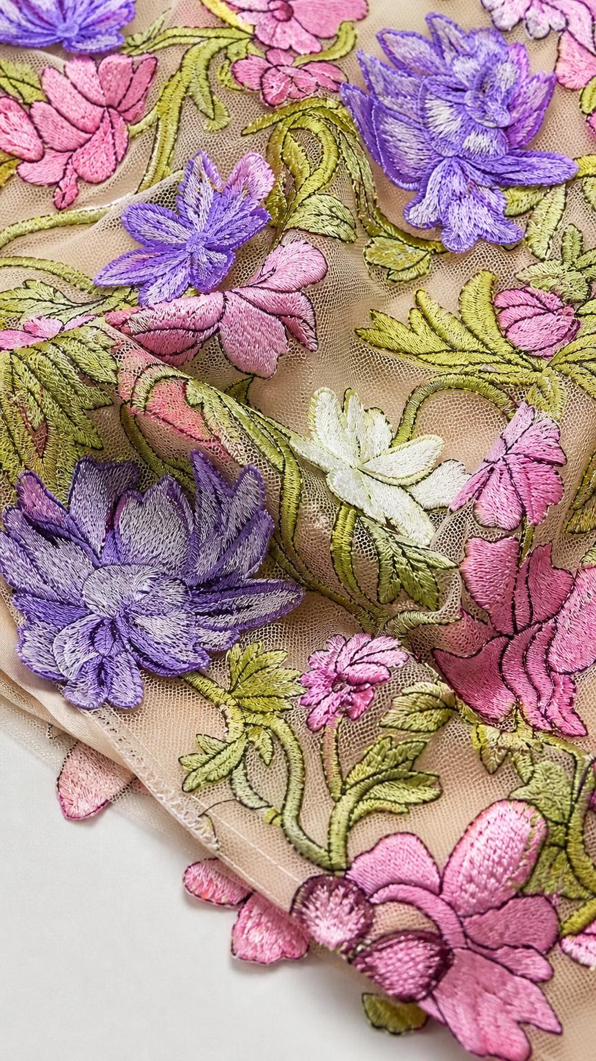 Close-up detail of multi-colored floral embroidery on sheer mesh