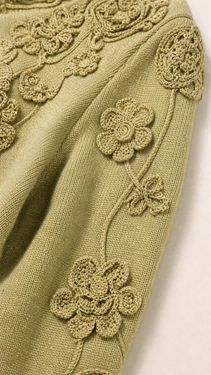 Close-up detail of crochet floral appliques on Sage Green knit sleeve