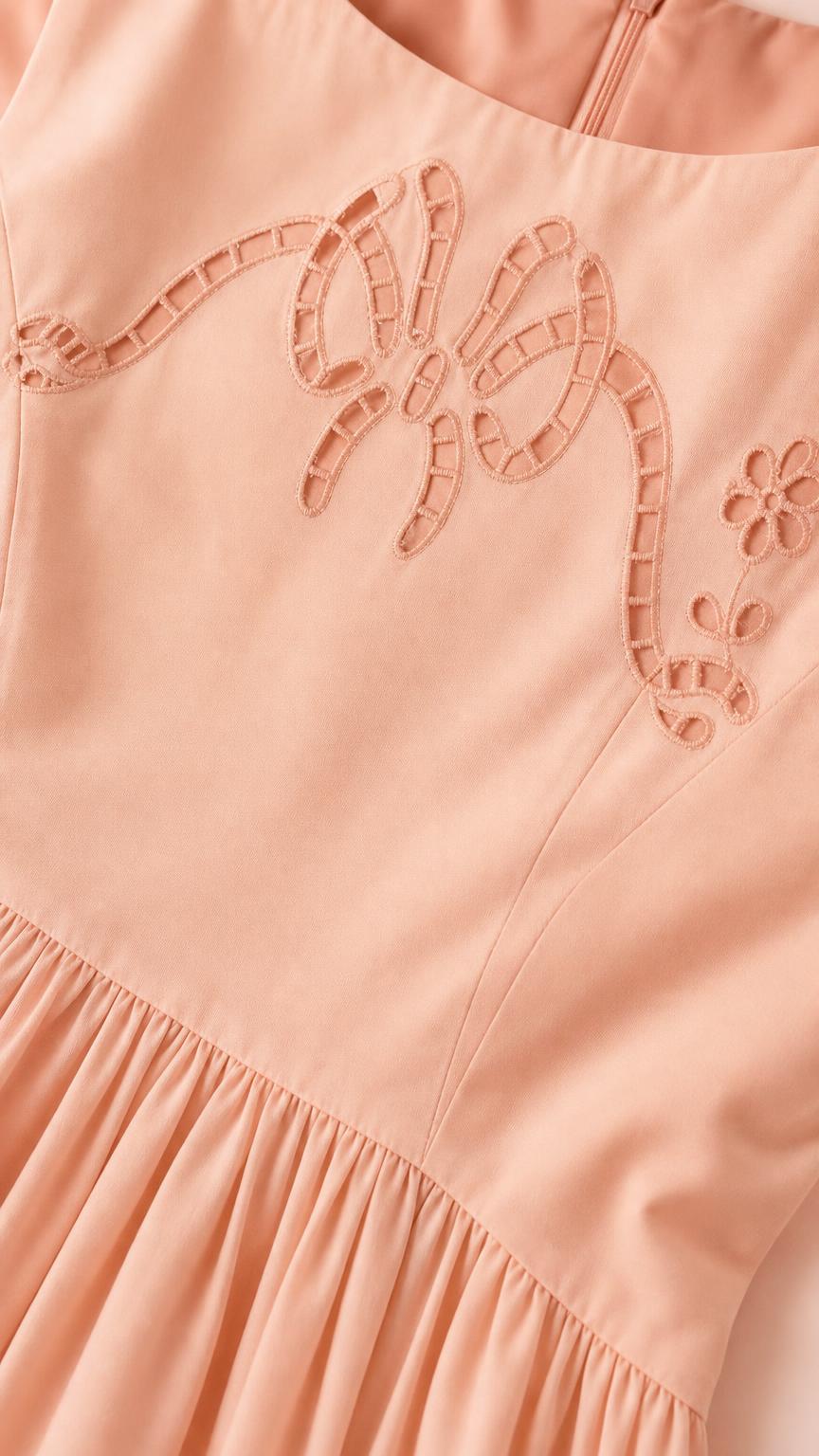 Close-up of cutwork bow embroidery on peach dress