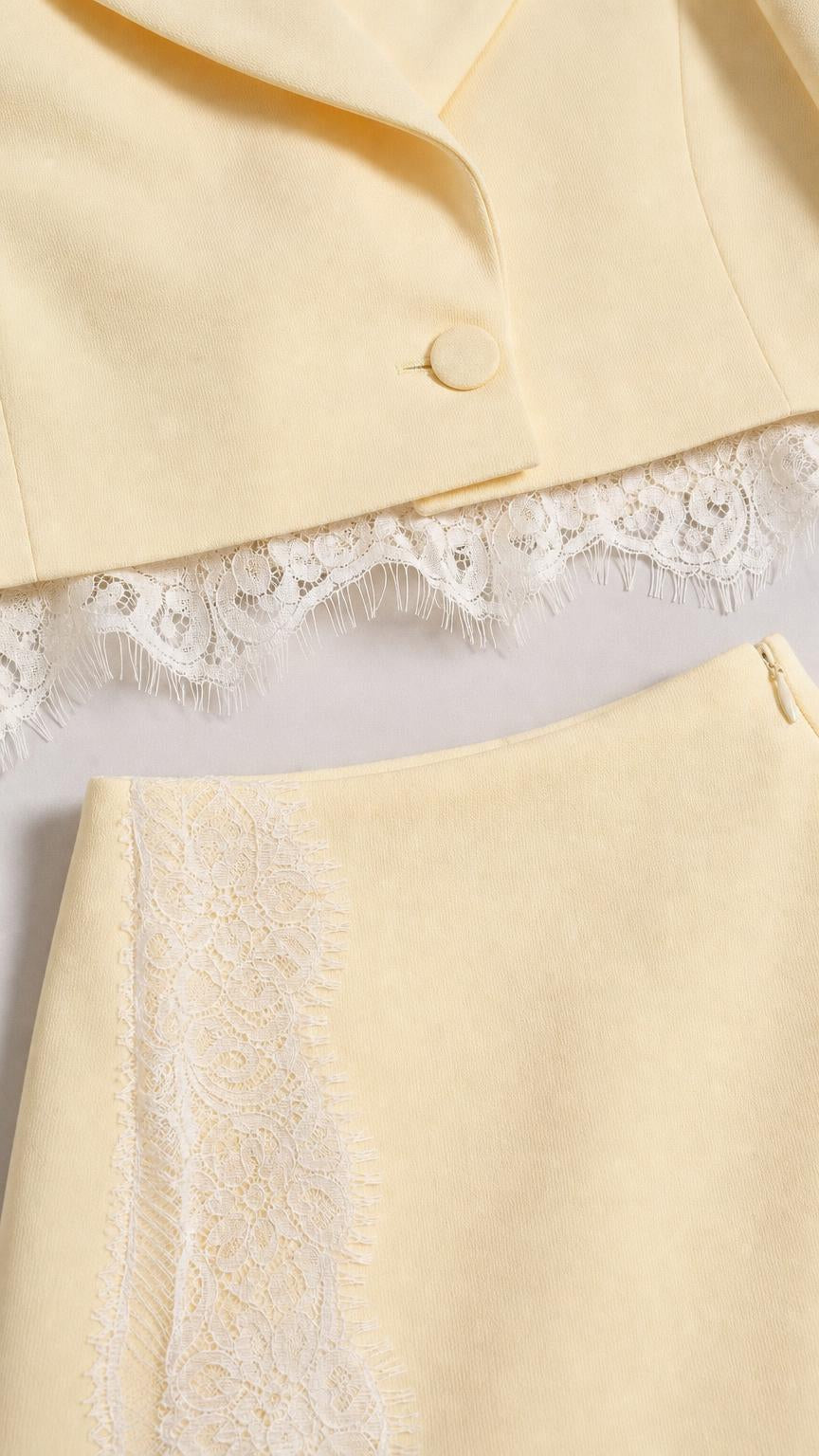 Close-up detail of the yellow blazer button and intricate lace hem on skirt and jacket
