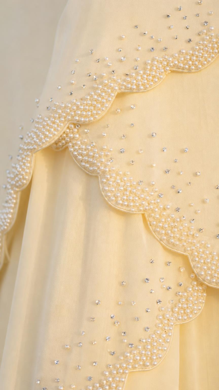 Close-up detail of pearl and crystal beadwork on scalloped tiers of yellow dress