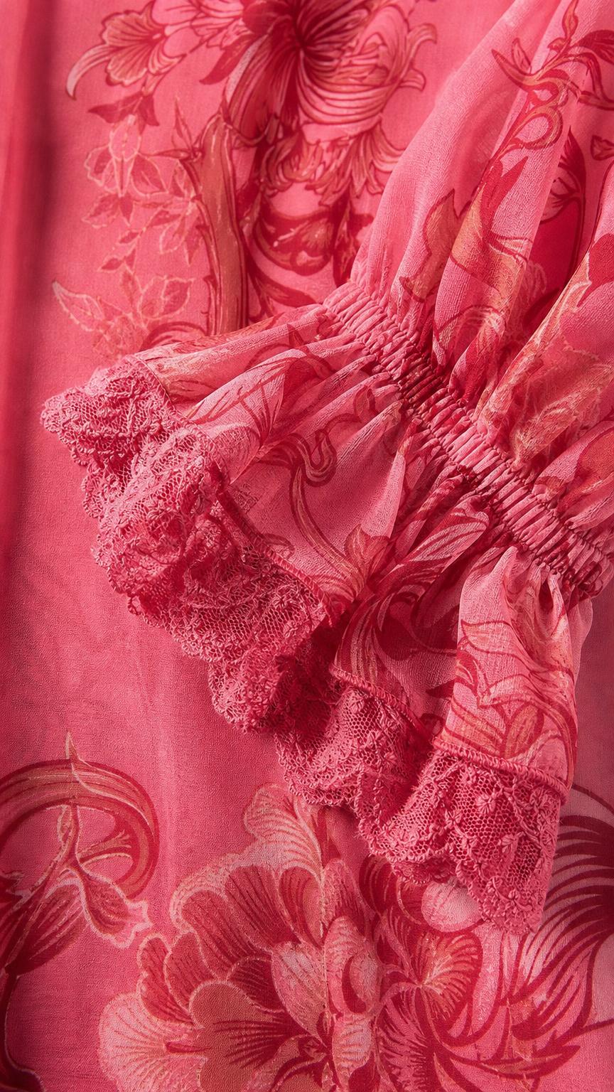 Close-up detail of lace-trimmed cuff and floral pattern on pink fabric