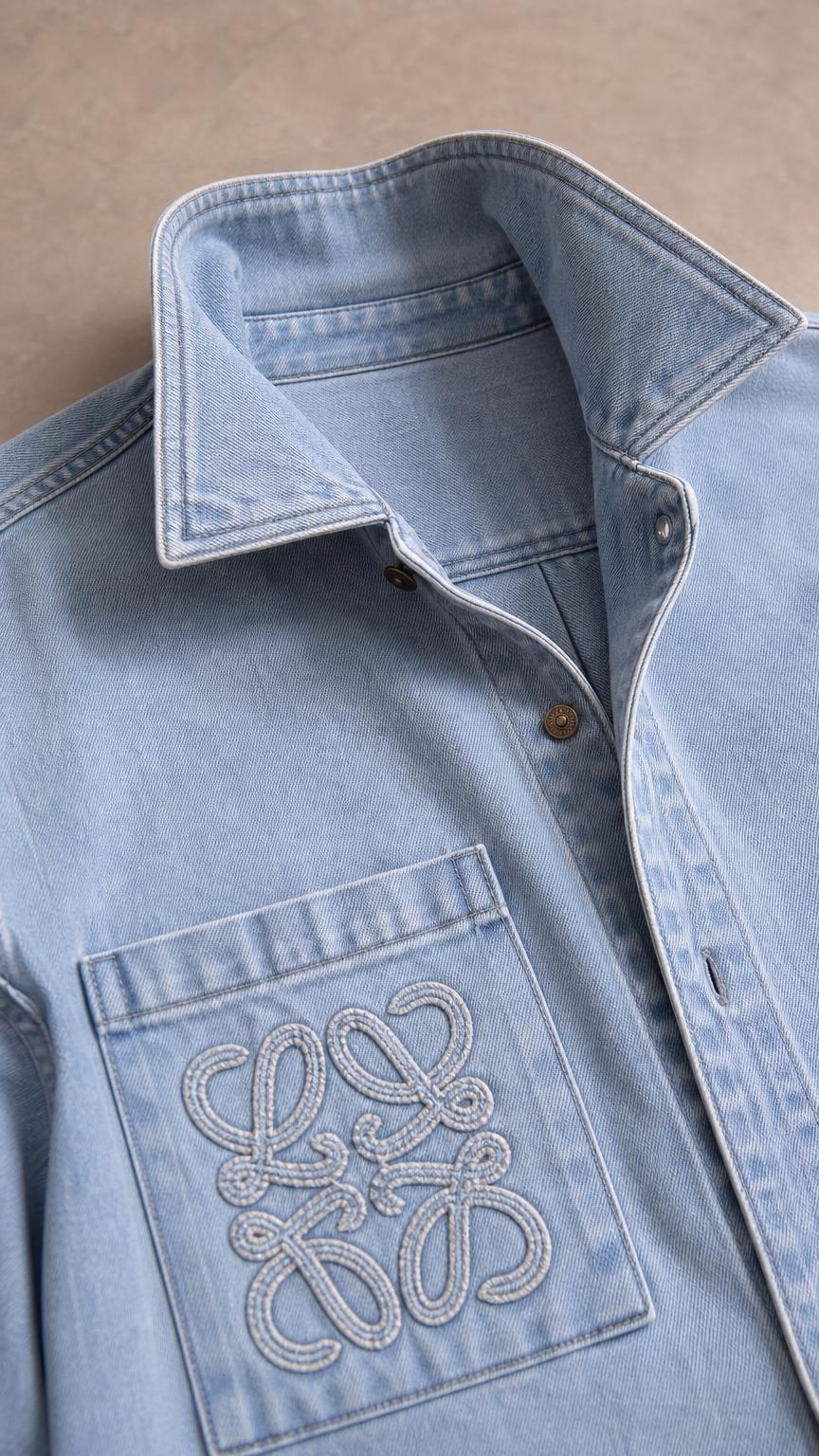 Close-up of light blue denim shirt collar and embroidered chest pocket