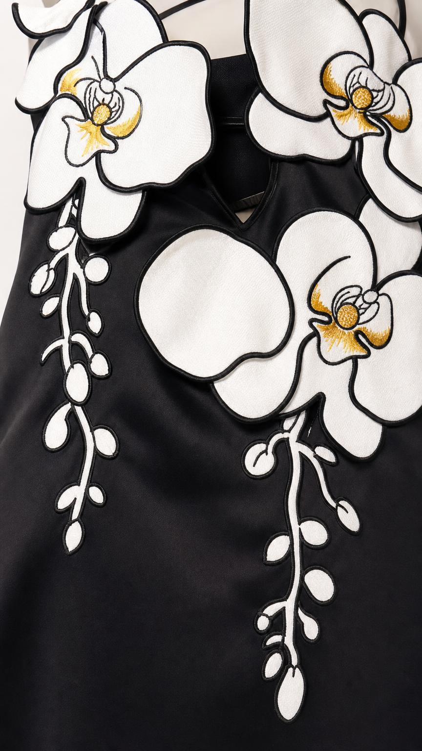 Close-up detail of the 3D white and yellow floral appliques on the black dress bodice