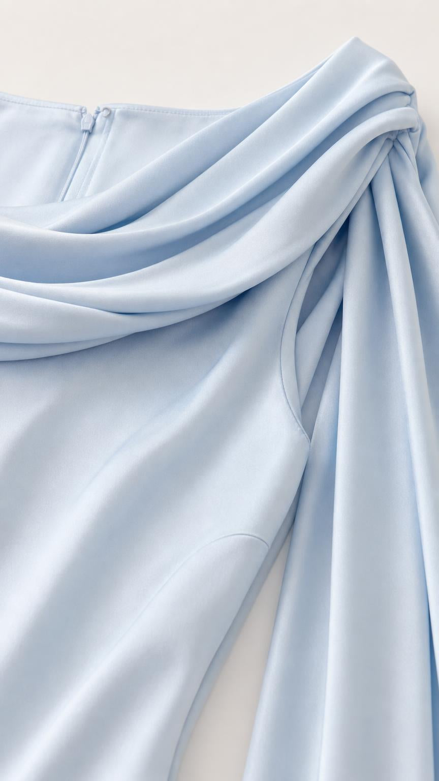 Close-up detail of smooth fabric and cowl shoulder draping in light blue