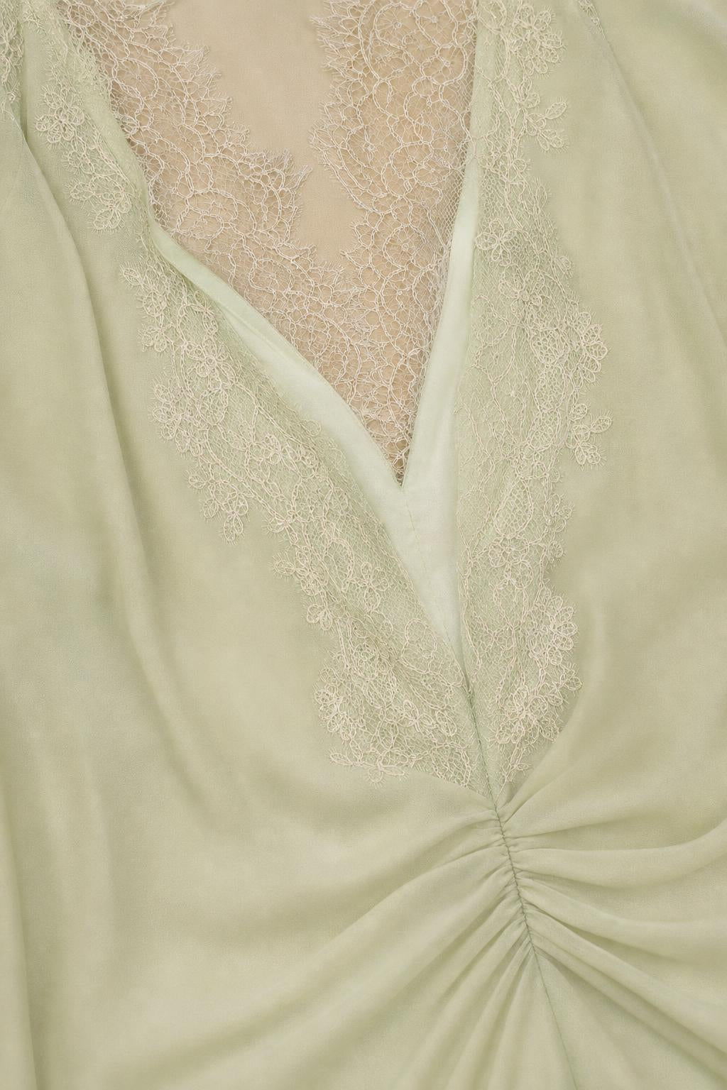 Close-up of V-neckline and lace trim detail in sage green