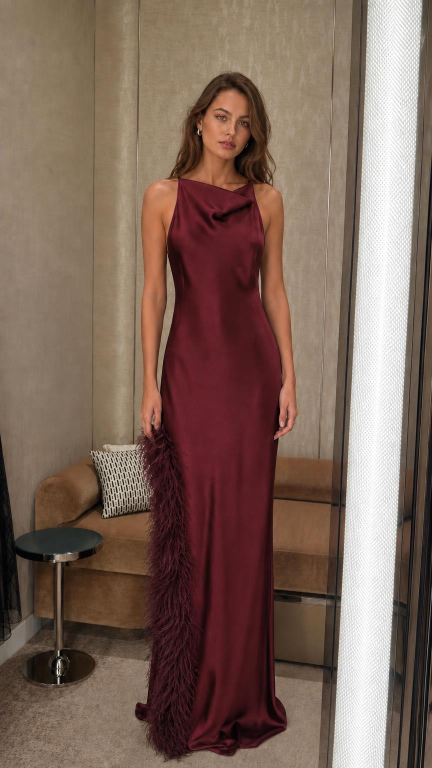 Woman wearing burgundy satin cowl neck maxi dress with feather trim