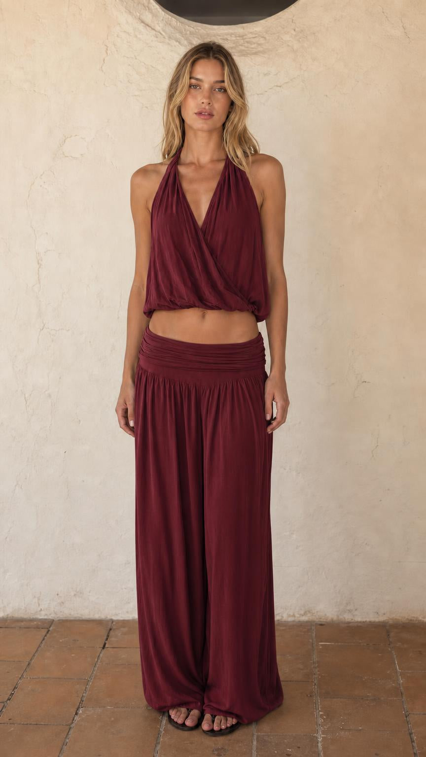 Woman wearing burgundy halter crop top and wide leg pants set